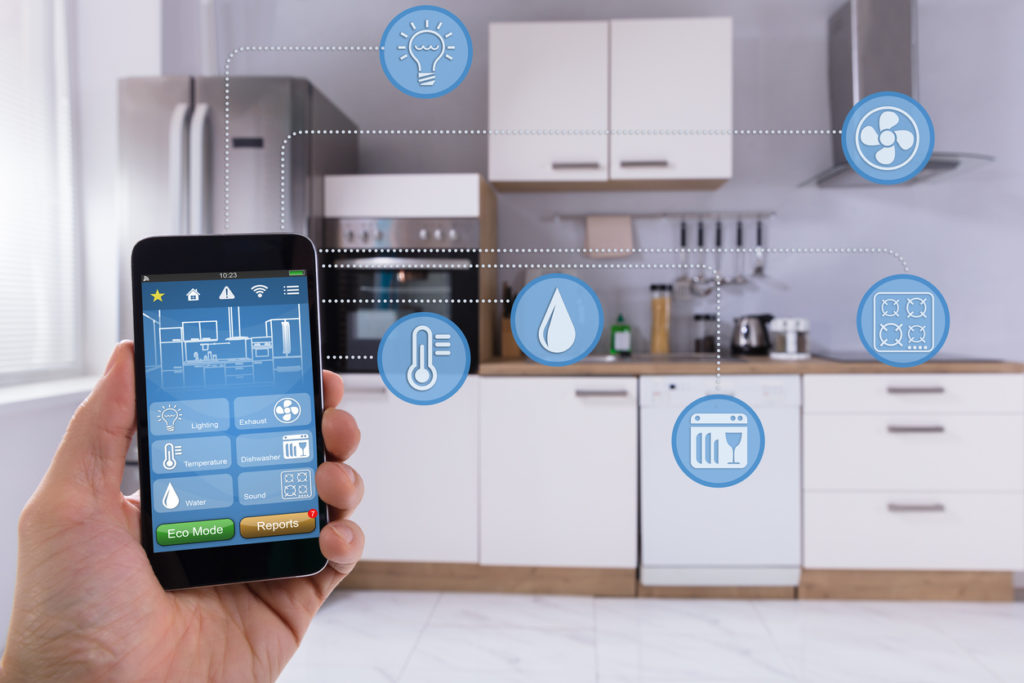 Close-up nan men yon moun ki sèvi ak aplikasyon Smart Home sou Smartphone nan kwizin